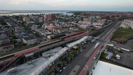 An-aerial-view-over-Arverne,-NY-by-an-elevated-train-station-and-an-empty-road
