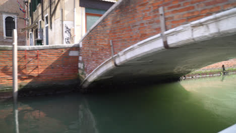 POV-Desde-Un-Barco-Que-Navega-Por-El-Canal-Que-Pasa-Por-Debajo-Del-Puente-De-Piedra-En-Venecia,-Italia