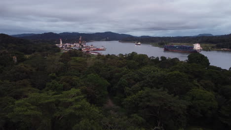 Flying-Above-Tropical-Rainforest-With-View-Of-Cargo-Ship-Sailing-On-The-Chagres-River-Near-Dredging-Division-Base-In-Panama-Canal,-Gamboa,-Panama
