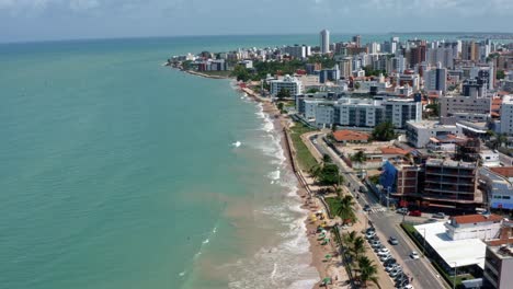 Tilting-up-aerial-drone-shot-of-the-tropical-beach-city-of-Cabedelo,-Brazil-from-the-intermares-beach-near-Joao-Pessoa-with-skyscrapers-along-the-coastline-in-the-state-of-Paraiba-on-a-summer-day