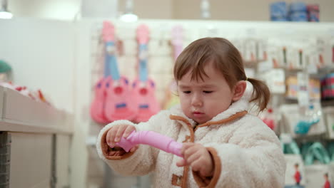 Neugieriges-Kleines-Mädchen,-Das-Im-Einkaufszentrum-Ein-Spielzeug-Ausprobiert
