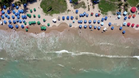 Bird's-eye-aerial-shot-of-intermares-beach-in-Cabedelo,-Brazil-with-Brazilians-and-tourists-enjoying-the-ocean-near-the-costal-capitol-of-Joao-Pessoa-in-the-state-of-Paraiba-on-a-warm-sunny-summer-day