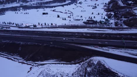 Traffic-hour-drone-footage-of-snowy-canadian-roads-with-the-Rocky-Mountains-on-background