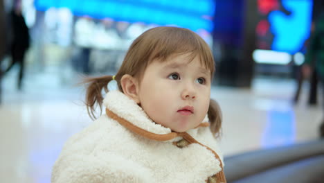 Cute-Little-Girl-Looking-Around-While-Munching-Food-At-The-Shopping-Mall