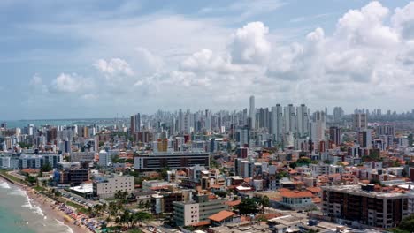 Trucking-right-aerial-shot-of-the-tropical-beach-city-of-Cabedelo,-Brazil-from-the-intermares-beach-near-Joao-Pessoa-with-skyscrapers-along-the-coastline-in-the-state-of-Paraiba-on-a-warm-summer-day