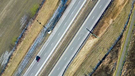 An-overhead-drone-shot-of-a-highway-in-the-winter-with-cars-passing-through-the-frame
