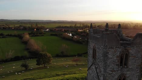 Aerial-backwards-reveal-shot-of-Burrow-Mump-Church-with-the-glow-of-a-sunset-over-the-somerset-levels