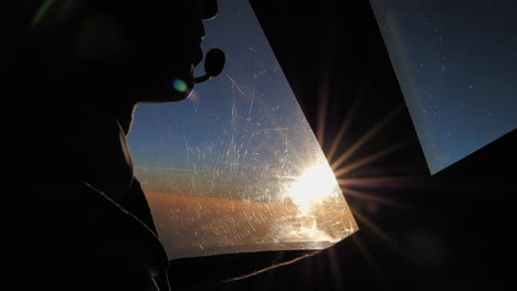 Nahaufnahme-Eines-Männlichen-Piloten-Im-Cockpit-Eines-Flugzeugs,-Der-Im-Radio-In-Zeitlupe-Spricht,-Im-Gegenlicht-Der-Untergehenden-Sonne