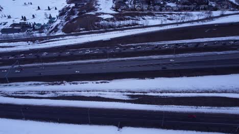 Sunset-aerial-drone-footage-of-frosty-snow-covered-highway-with-cars