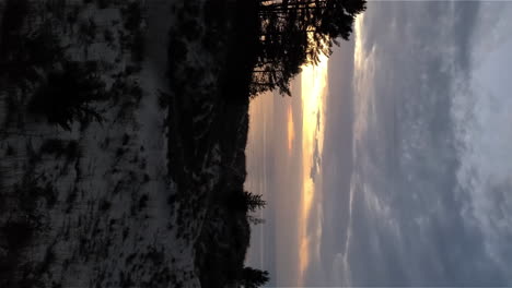 Vertical-footage-of-stunning-sunset-in-cloudy-sky-over-ocean,-dunes-in-the-foreground