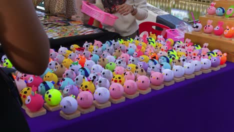Close-up-shot-of-roadside-stall-selling-toy-souvenirs-in-Khlong-Hae-floating-market-in-Songkhla-province,-Thailand-on-a-busy-day