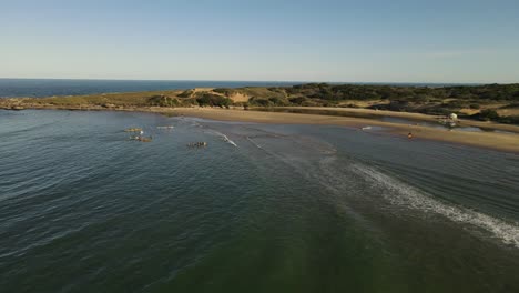 Aerial-view-of-kayaks-arriving-shore-of-Playa-Grande-Beach-in-Uruguay-during-golden-sunset