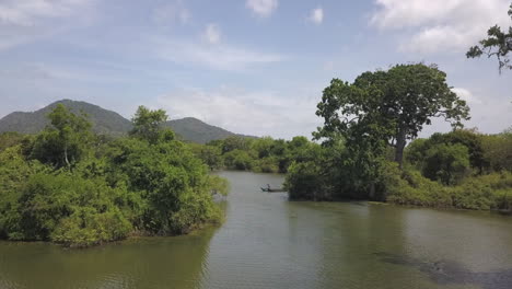 Sri-Lankan-men-in-canoe-boat-paddle-in-Yala-swamp-wetland,-low-aerial