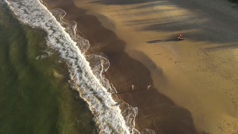 Aerial-Orbit-shot-of-family-day-at-sandy-beach-with-playing-kids-during-golden-sunset---slow-motion