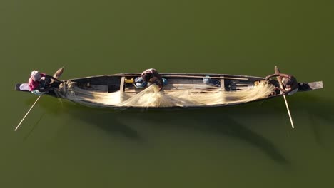 Luftaufnahme-Eines-Kleinen-Holzbootes-Mit-Fischern,-Die-Im-Traditionellen-Stil-Im-Fluss-Surma,-Bangladesch,-Fische-Mit-Einem-Netz-Fangen