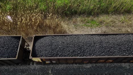 Coal-train-with-resources-driving-on-tracks,-aerial-downwards-view