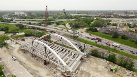 Network-Tied-Arch-Bridge-being-built-next-to-I94-freeway,-aerial-orbital-shot,-Detroit,-Michigan,-USA