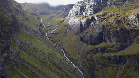 Steep-whitewater-creek-runs-down-steep-craggy-mountain-highland-valley
