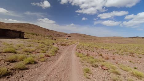 Point-of-view-of-a-driver-passing-next-to-a-lonely-school-in-the-desertic-High-Atlas-mountains-in-Morocco