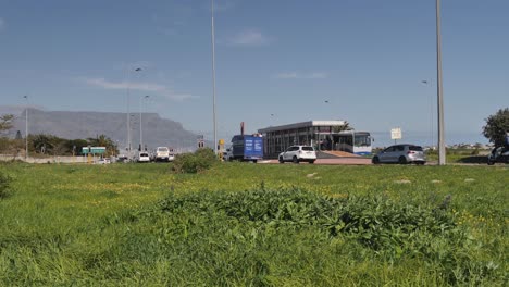 Vehicle-traffic-drives-past-bus-stop-shelter-in-Cape-town,-Table-Mountain