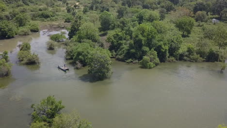 Jungle-aerial-descends-to-men-paddling-canoe-raft-in-flooded-swamp
