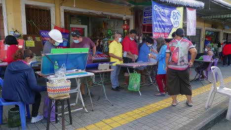 Shot-of-people-buy-lottery-from-a-roadside-stall-in-Songkhla-Province,-Thailand-at-daytime