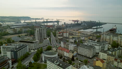 Sunset-over-Gdynia-port-and-city-buildings-panorama,-aerial-pull-back-shot