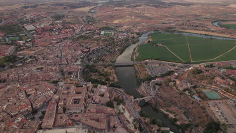 Panning-cityscape-aerial-view-of-ancient-city-Toledo,-Spain,-El-Alcazar,-Alcantara-Bridge