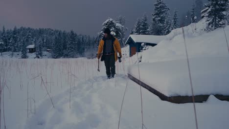Hombre-Con-Hacha-Y-Matraz-De-Vacío-Caminando-Sobre-La-Nieve-En-Invierno