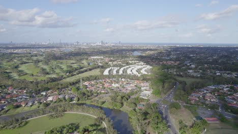 Aerial-View-Of-The-Town-Of-Robina-On-A-Sunny-Day-In-Gold-Coast,-Queensland-With-Coastal-Skyline-In-Distant-Background
