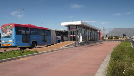 Pan-with-long-articulated-transit-bus-pulling-into-bus-stop,-Cape-town