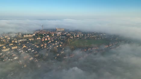 Aerial-drone-point-of-view-English-cityscape-shot-during-sunrise,-glowing-sun-on-cloudy-misty-sky,-picturesque-scenery