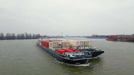 29-January-2023---Aerial-Circle-Dolly-Around-Forward-Bow-Of-Denford-Cargo-Ship-Partnered-With-Barge-Transporting-Containers-Along-Oude-Maas