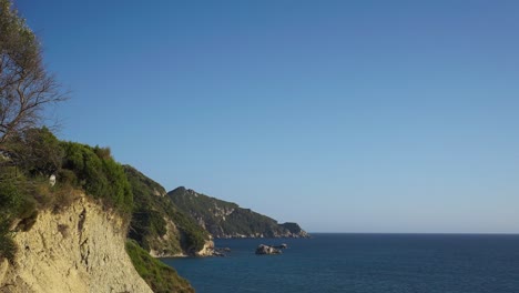 Corfu-coastline-in-Greece,-turquoise-water-of-mediterranean-sea-on-sunny-day-Establisher-pan-shot-of