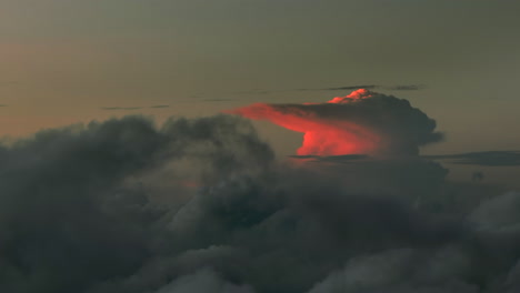 Aerial-flight-above-dark-clouds-illuminated-by-sun-behind-horizon