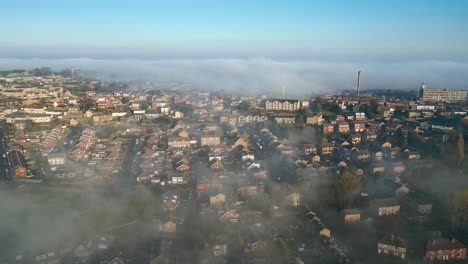 Cinematic-aerial-view-of-town-city-with-residential-buildings-in-earning-fog-and-mist