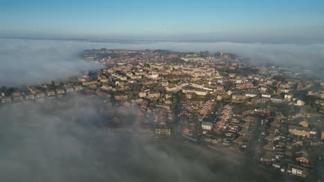 Aerial-view-of-town-city-with-residential-buildings-in-earning-fog-and-mist