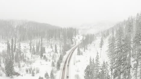Aerial-shot-over-winding-road-through-snowy-pine-forest