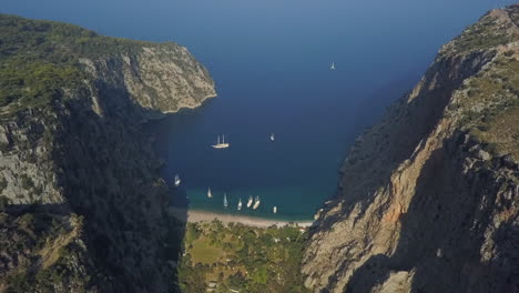 Aerial:-Tour-ships-moored-in-steep-mountain-Butterfly-Valley,-Turkey
