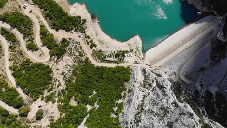 Aerial-birdseye-flying-over-access-road-to-Lake-Bovilla,-revealing-turquoise-waters