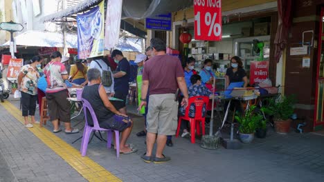 Shot-of-locals-crowding-towards-the-tables-to-buy-lottery-tickets-in-Songkhla-Province,-Thailand-at-daytime