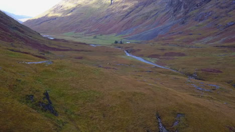 Aerial-ascends-over-hill-top-to-reveal-remote-river-valley-in-Scotland