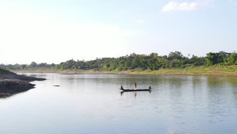 Toma-Aérea-De-Un-Pequeño-Bote-De-Madera-Con-Pescadores-Capturando-Peces-Usando-Una-Red-Al-Estilo-Tradicional-En-El-Río-Surma,-Bangladesh