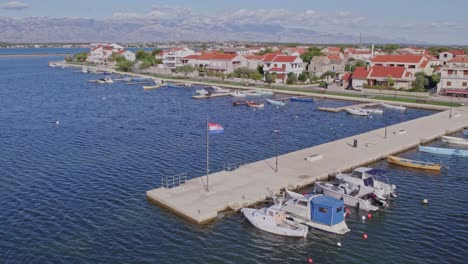 Small-boats-anchored-at-concrete-harbor-of-Nin-in-Croatia,-aerial
