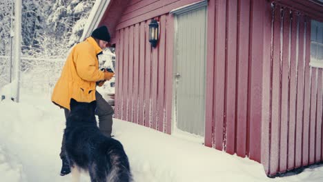Kaukasischer-Mann-Mit-Hund-Alaskan-Malamute,-Der-Im-Winter-Eine-Hütte-Betritt