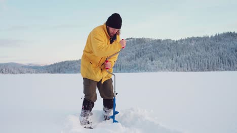 Norwegian-Guy-Is-Drilling-With-Ice-Auger-On-A-Frozen-Lake