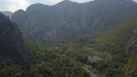 Aerial-flight-up-hazy-rock-mountain-forest-river-valley,-Turkey