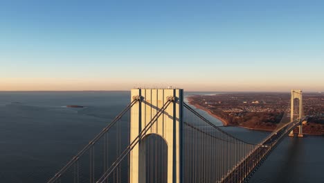 Aerial-view-away-from-the-Verrazzano-Narrows-bridge,-golden-hour-in-New-York,-USA---reverse,-drone-shot