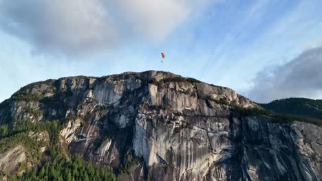 Person-Paragliding-Over-Mountainous-Landscape-Of-Stawamus-Chief-In-British-Columbia,-Canada
