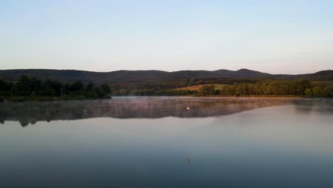 Morning-sunlight-hits-shore-of-tranquil-lake-near-Varbo,-Hungary